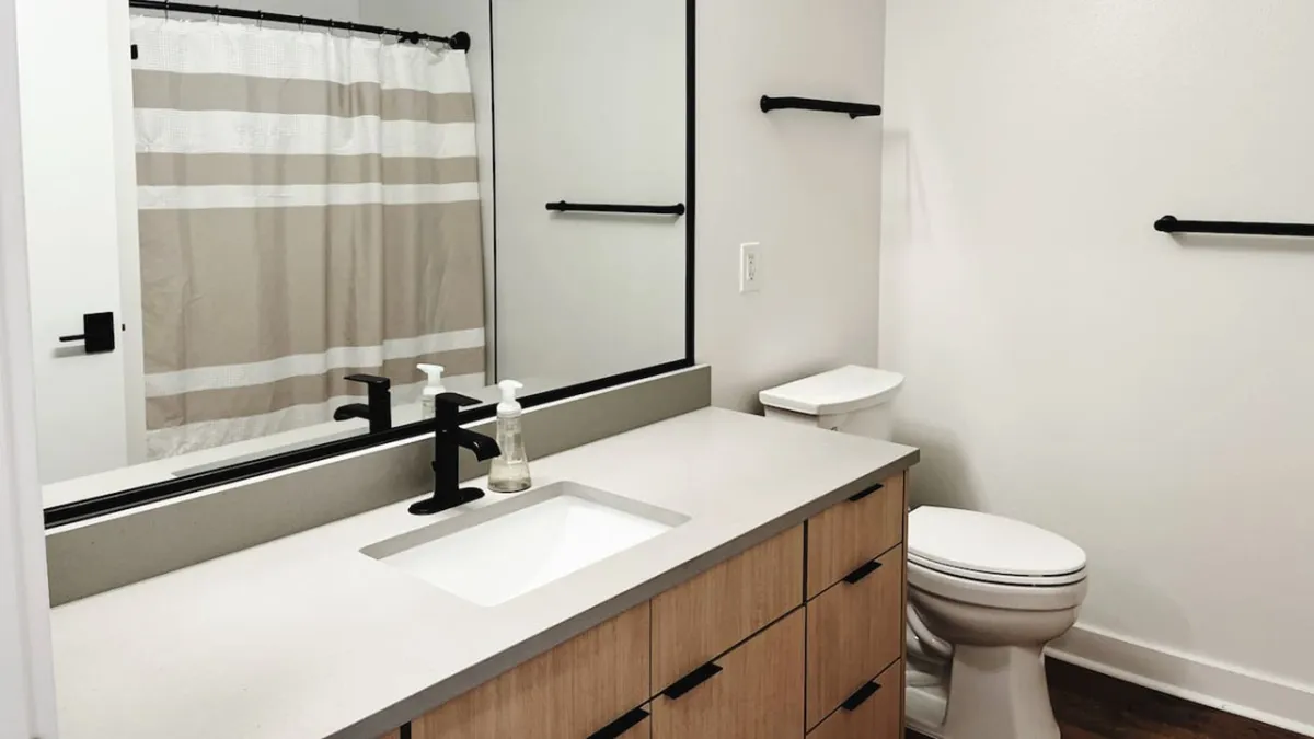 A serene bathroom interior with a sleek vanity, large mirror, and a glimpse of the spacious layout. The tranquil mood and soft lighting evoke a spa-like environment, ideal for unwinding during a relaxing bath or completing a daily self-care routine.