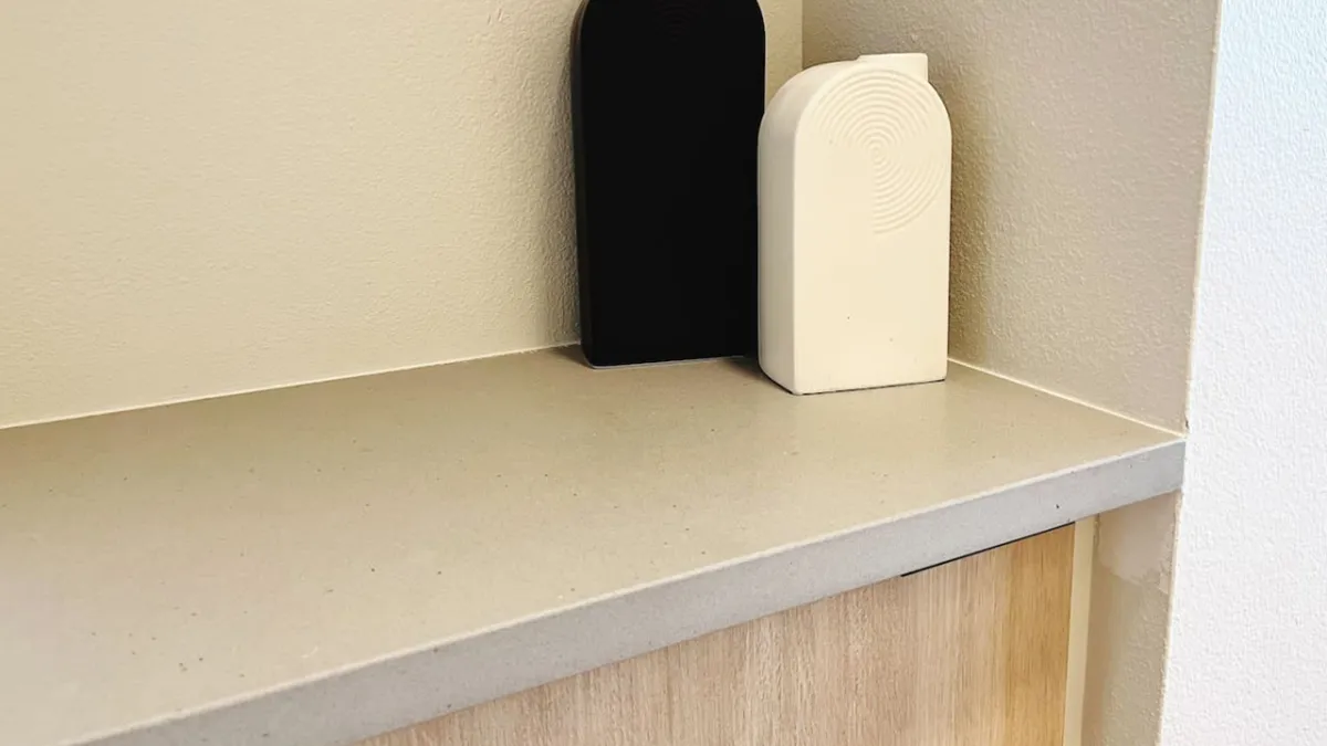 A contemporary interior shot showcases a minimalist countertop, adorned with a few stylish black and white objects. The clean design and uncluttered surface suggest a dining or kitchen area tailored for relaxed meals or coffee breaks.
