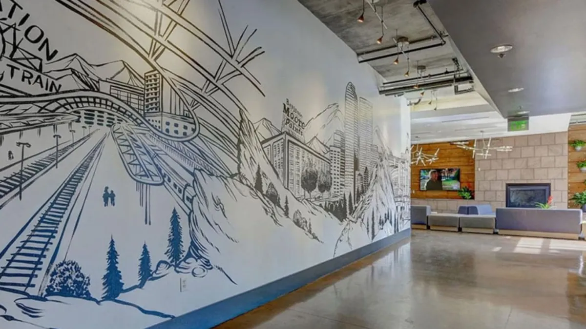 This interior shot features a stylish lounge area with a large, vibrant mural as the focal point. Modern seating arrangements and contemporary lighting create a welcoming environment perfect for social gatherings, informal meetings, or enjoying community art. The setting suggests a space where residents can relax, connect, and enjoy amenities that echo boutique hotel experiences.