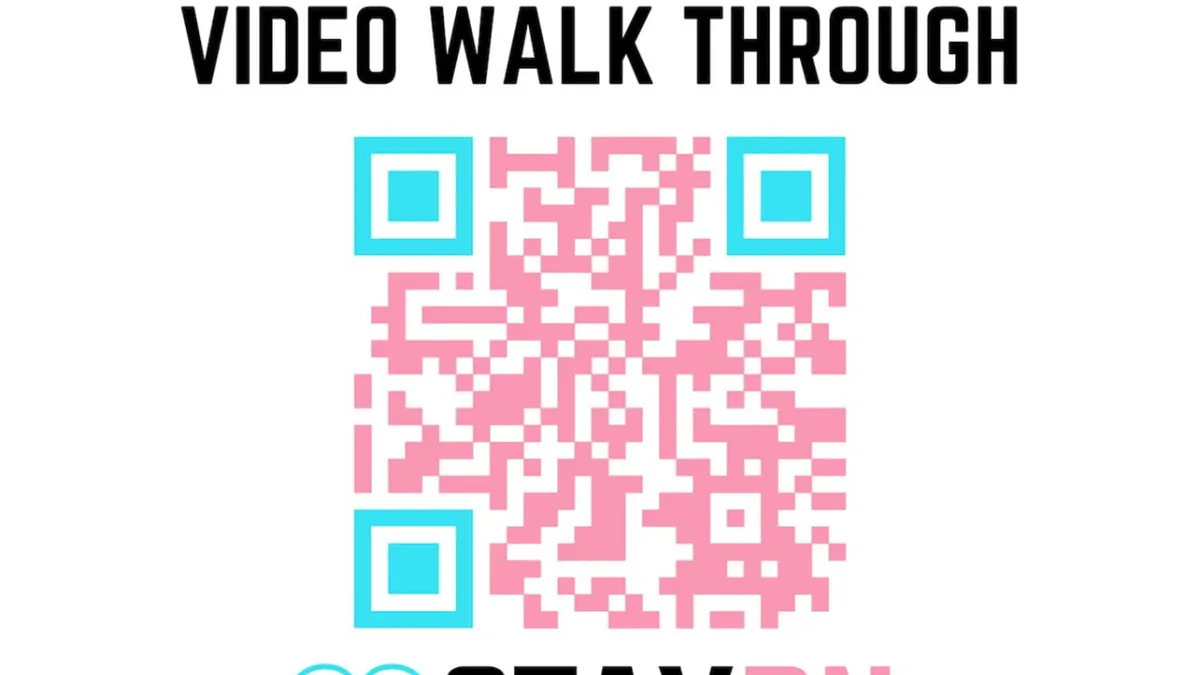 This image depicts an interior scene focused on a QR code and accompanying text instructions, likely for accessing an immersive video walkthrough or digital amenities. The surrounding area appears modern and organized, hinting at a tech-forward, welcoming environment.
